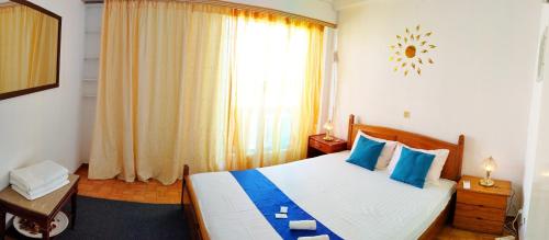 sypialnia z łóżkiem z niebieskimi poduszkami i oknem w obiekcie Cozy room in quiet neighbourhood w Atenach