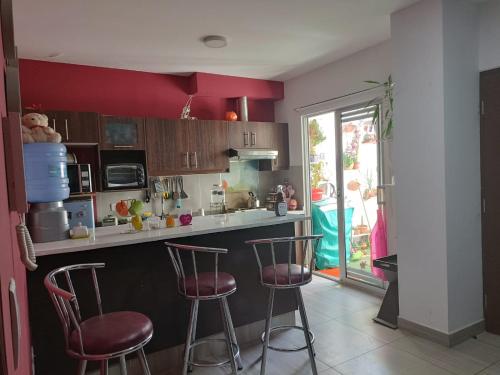 a kitchen with red walls and two bar stools at Apartment Matisse in Cochabamba
