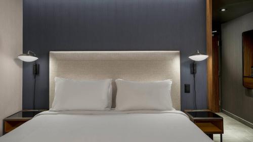 a large white bed with two pillows and two lights at Courtyard by Marriott San Diego Miramar in San Diego