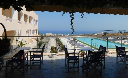 un patio con mesas y sillas y vistas a la piscina en fira blue horizon, en Fira