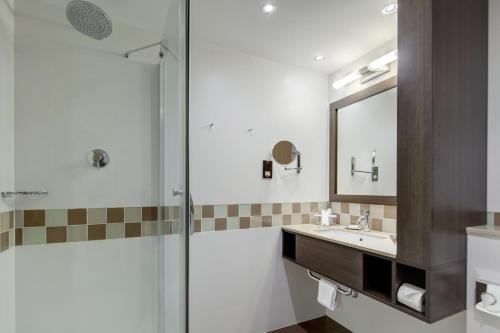 a bathroom with a shower and a sink and a mirror at Hilton Dublin Kilmainham in Dublin