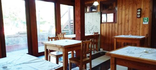um restaurante com mesas e cadeiras de madeira e uma janela em Hostal Florencia em Puerto Varas