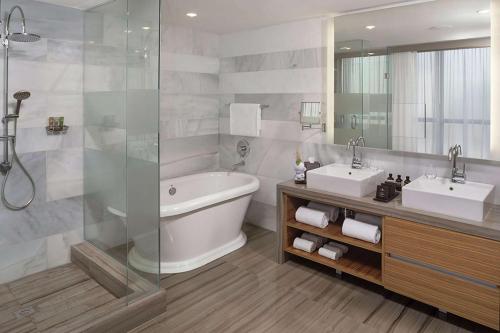 a bathroom with two sinks and a tub and a shower at The Gabriel Miami Downtown, Curio Collection by Hilton in Miami