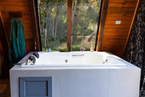 uma banheira branca num quarto com uma janela em Cabana com Hidromassagem e Vista, a 12km de Treze Tílias em Ibicaré