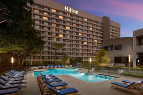 Hilton Los Angeles-Culver City, CA في لوس أنجلوس: فندق فيه مسبح وكراسي صالة