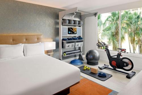 a bedroom with a bed and a room with a gym at Hilton Los Angeles-Culver City, CA in Los Angeles