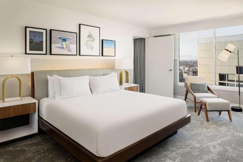 a bedroom with a large white bed and a chair at Hilton Los Angeles-Culver City, CA in Los Angeles