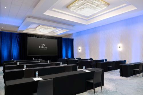 a conference room with tables and chairs and a screen at Hilton Los Angeles-Culver City, CA in Los Angeles