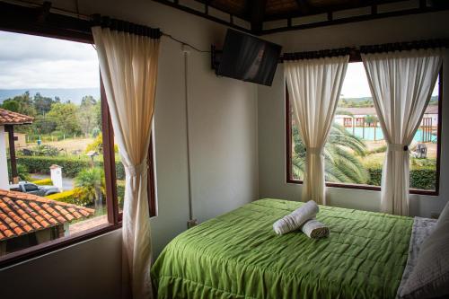 a bedroom with a green bed and a large window at El Pozzo Hotel Campestre in Villa de Leyva