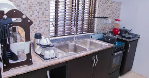 a kitchen with a sink and a stove at JEFA Deluxe Suites in Lagos