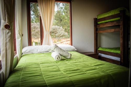 a bedroom with a green bed with a window at El Pozzo Hotel Campestre in Villa de Leyva