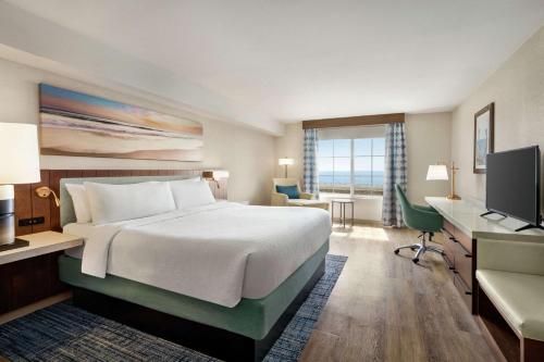 a hotel room with a bed and a desk and a television at Hilton Garden Inn Carlsbad Beach in Carlsbad