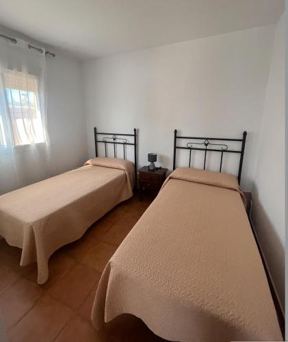 twee bedden in een kamer met een raam bij Villa Lago Mayor in Chiclana de la Frontera