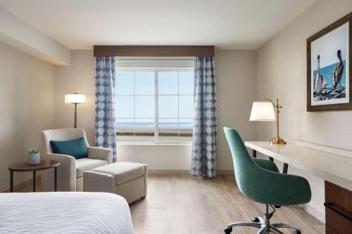 a hotel room with a bed and a desk and a window at Hilton Garden Inn Carlsbad Beach in Carlsbad