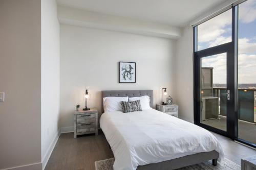 a white bedroom with a bed and a large window at Luxury 2bdrm Penthouse in Midtown in Atlanta