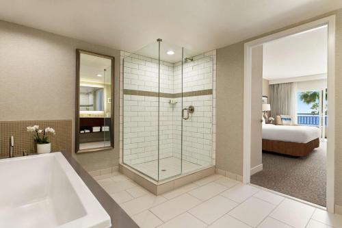 a bathroom with a shower and a tub and a bed at Cape Rey Carlsbad Beach, A Hilton Resort & Spa in Carlsbad