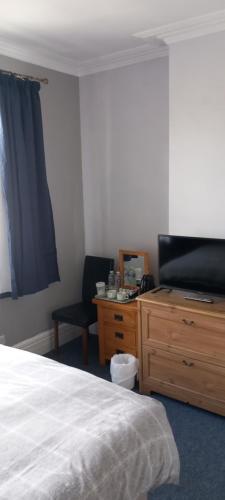 a bedroom with a bed and a desk and a television at Ty Castell Guest House in Caerphilly