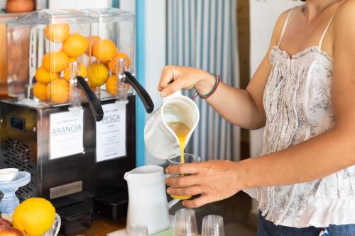 a woman pouring orange juice into a blender at Hotel Riva Etrusca in Marina di Bibbona