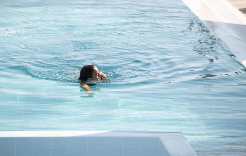 a woman swimming in a pool of water at Aetherion Studios & Suites in Kalyves Poligirou