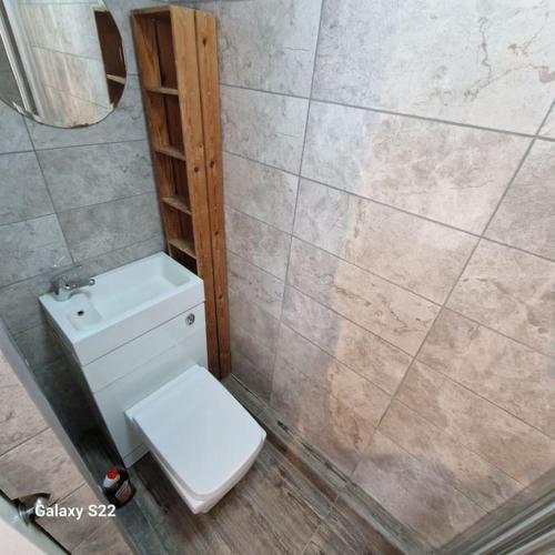 a bathroom with a white toilet and a tiled wall at Quiet and cozy studio in Hendon