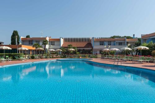 a large blue swimming pool with chairs and umbrellas at Hotel Riva Etrusca in Marina di Bibbona