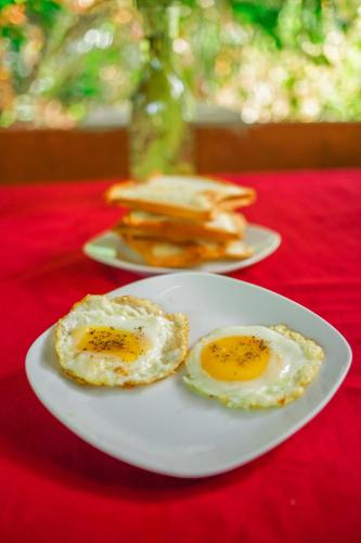 two fried eggs on a white plate on a red table at Dambulla Kings Inn in Dambulla