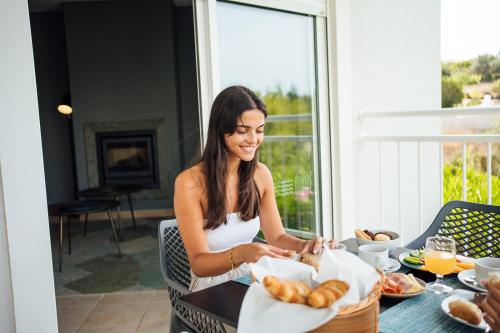 a woman sitting at a table with a basket of bread at Placid Village in Carvoeiro