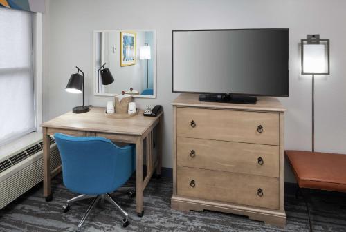 a room with a desk and a tv and a blue chair at Hampton Inn Austin Round Rock in Round Rock