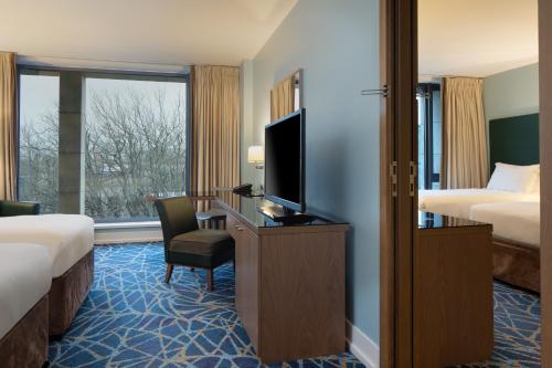 a hotel room with two beds and a desk with a television at Hilton Dublin Kilmainham in Dublin