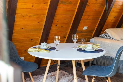 una mesa blanca con 2 vasos y 2 sillas en Cabana com Hidromassagem e Vista, a 12km de Treze Tílias en Ibicaré