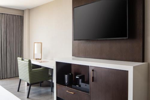 a hotel room with a desk and a flat screen tv at Dallas-Addison Marriott Quorum by the Galleria in Addison