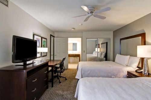 a hotel room with two beds and a desk with a television at Homewood Suites by Hilton Newark-Cranford in Cranford