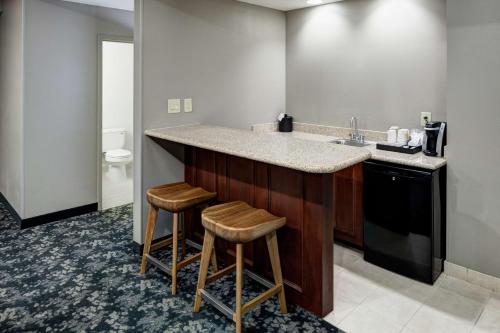 a kitchen with a sink and two stools at a counter at Hilton Garden Inn Nashville Vanderbilt in Nashville