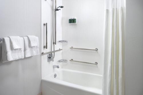 a white bathroom with a tub and a shower at Courtyard Charlotte SouthPark in Charlotte