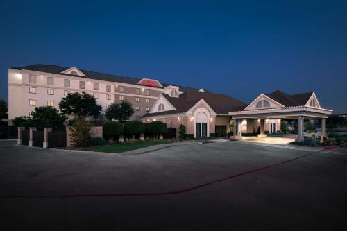 a large building with a driveway in front of it at Hilton Garden Inn Las Colinas in Irving