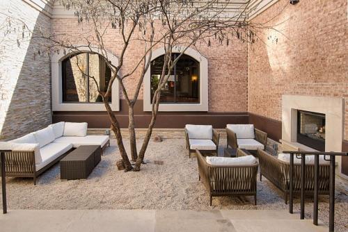 eine Terrasse mit Sofas, einem Baum und einem Kamin in der Unterkunft Hilton Garden Inn Las Colinas in Irving