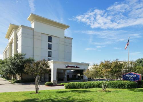 um edifício de hotel com uma bandeira americana em frente em Hampton Inn Dallas Irving Las Colinas em Irving