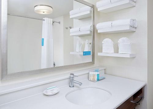 a bathroom with a sink and a mirror and towels at Hampton Inn Dallas Irving Las Colinas in Irving