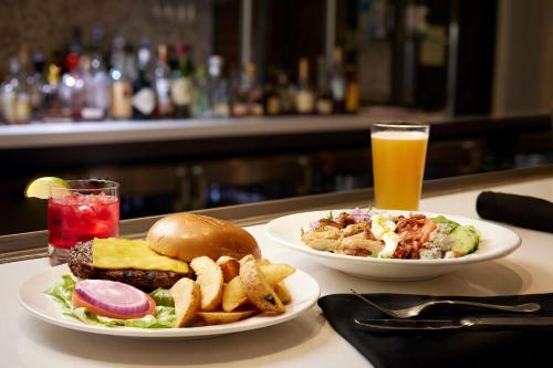 a table with two plates of food and a drink at Hilton Garden Inn Las Colinas in Irving