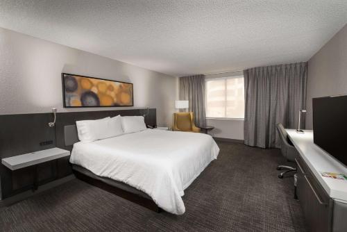 a hotel room with a white bed and a window at Hilton Garden Inn Las Colinas in Irving