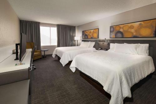 a hotel room with two beds and a television at Hilton Garden Inn Las Colinas in Irving