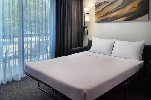 uma grande cama branca num quarto com uma janela em Courtyard by Marriott Augusta em Augusta