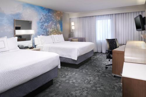 um quarto de hotel com duas camas e uma secretária em Courtyard Cleveland Airport North em North Olmsted