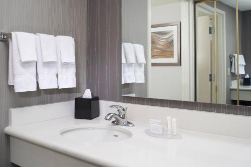 W łazience znajduje się umywalka, lustro i ręczniki. w obiekcie Courtyard Cleveland Airport North w mieście North Olmsted
