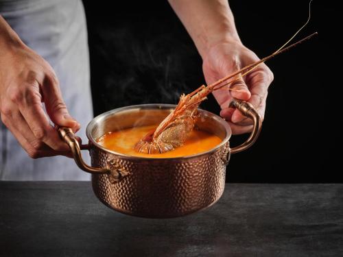 a person stirring a pot of food with chopsticks at Crowne Plaza Suzhou by IHG in Suzhou