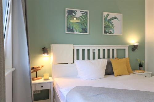 - une chambre avec un lit doté de draps blancs et d'oreillers jaunes dans l'établissement Haus am Meer Haus am Meer, App 01, à Neuhaus
