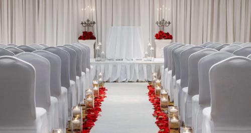 a row of chairs with a aisle with red flowers at Hilton Indianapolis Hotel & Suites in Indianapolis