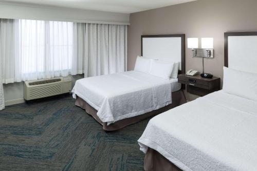 a hotel room with two beds and two windows at Hampton Inn Los Angeles Orange County Cypress in Cypress