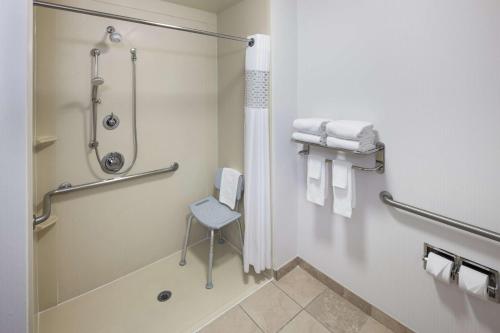 a bathroom with a shower and a chair in it at Hampton Inn Los Angeles Orange County Cypress in Cypress