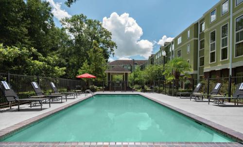 a swimming pool with lounge chairs and a building at Homewood Suites Lafayette-Airport in Lafayette